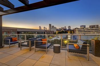 A patio with chairs and a table with a view of the city.
